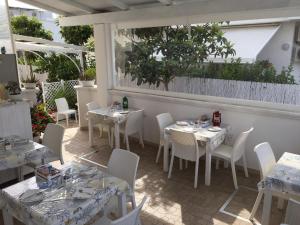 un ristorante con tavoli bianchi e sedie bianche di Nonna Pina a Torre Canne