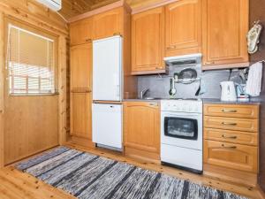 a kitchen with wooden cabinets and a white refrigerator at Holiday Home Eden by Interhome in Kuusa