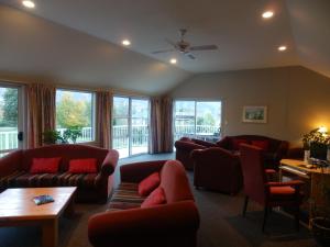 a living room with couches and chairs and windows at Lake Wanaka Lodge in Wanaka