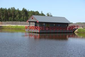a house on a dock on a body of water at Karpu dīķis-Kempings Viesītes in Jaunmārupe