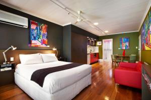 a bedroom with a white bed and a red chair at Tolarno Hotel in Melbourne