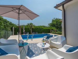 patio z krzesłami i parasolem przy basenie w obiekcie Holiday Home Villa Joy by Interhome w mieście Novigrad