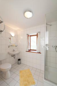 a white bathroom with a toilet and a sink at Pension Poschmühle in Traunreut