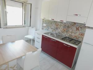 eine Küche mit roten Schränken, einer Spüle und einem Tisch in der Unterkunft Vanilla Apartments in Giardini-Naxos