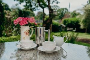 a table with two tea cups and a vase with roses at Apple Tree Bed and Breakfast in Tavistock