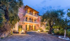 a large pink house with trees in front of it at Villa Maria Makri in Paleokastritsa