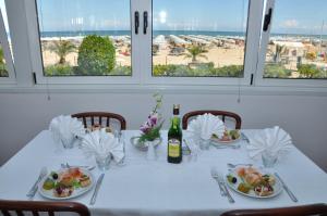 un tavolo con piatti e una bottiglia di vino di Hotel Driade sul mare a Rimini