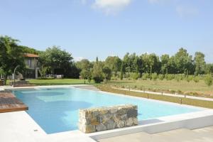 a large swimming pool in a yard with trees at Podere del Priorato in Albinia