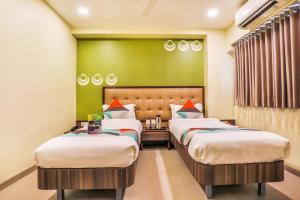 um quarto de hotel com duas camas e uma parede verde em FabHotel Landmark Guestline Vashi em Navi Mumbai