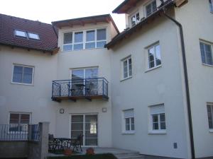 biały budynek z balkonem i stołem w obiekcie Haubis Ferienwohnungen w mieście Podersdorf am See