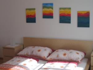 a bedroom with a bed with four paintings on the wall at Haubis Ferienwohnungen in Podersdorf am See