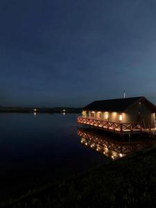 una casa en un muelle en el agua por la noche en Karpu dīķis-Kempings Viesītes, en Jaunmārupe