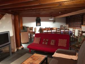 sala de estar con sofá rojo y mesa en LE SAPORTA- Studios et Appartements meublés de tourisme, en Le Lioran