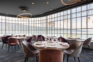 un restaurant avec des tables et des chaises et de grandes fenêtres dans l'établissement Le Palace De Menthon, à Menthon-Saint-Bernard 67 autres photos