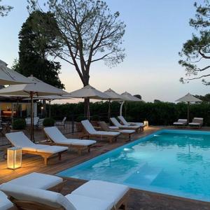 una piscina con sedie a sdraio e ombrelloni di Casa tua Spa Resort a Porto Recanati
