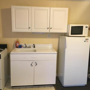 a kitchen with a sink and a white refrigerator at Clarence Inn Extended Stay in Clarence Center