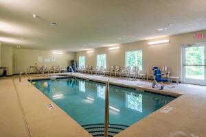 a large swimming pool with chairs and a person in a gym at Cobblestone Hotel & Suites - Harborcreek in Erie