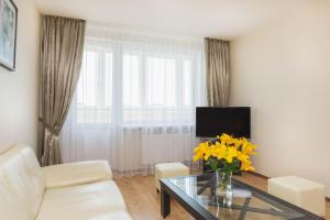sala de estar con sofá y mesa con flores amarillas en Apartment Amber Sky, en Palanga