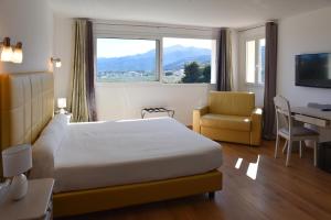 a hotel room with a bed and a chair and a window at Castellu Rossu in Lucciana