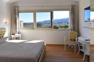 a bedroom with a bed and a table and two windows at Castellu Rossu in Lucciana