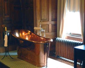 a bath tub sitting inside of a room next to a window at Tulloch Castle Hotel ‘A Bespoke Hotel’ in Dingwall