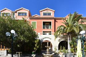 un grand bâtiment rose avec un palmier et une fontaine dans l'établissement Castellu Rossu, à Lucciana
