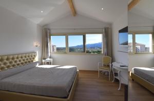 a bedroom with a bed and a desk and two windows at Castellu Rossu in Lucciana