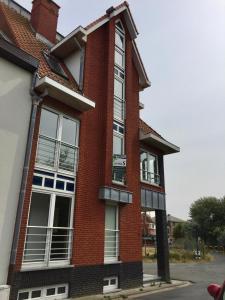 a red brick building with white windows on a street at North Sea Cottage Middelkerke in Middelkerke