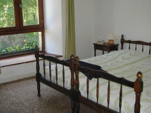 ein Schlafzimmer mit einem Holzbett und einem Fenster in der Unterkunft La Fontaine des Thiolles in Saint-Germain-lʼHerm