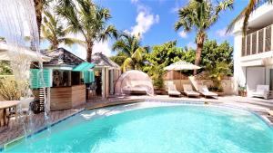 a swimming pool with chairs and an umbrella next to a house at Hotel Les Ondines Sur La Plage in Gustavia