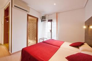 a bedroom with a red and white bed and a window at Hostal Sol in Toledo