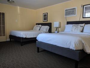 two beds in a hotel room with white sheets at Clarence Inn Extended Stay in Clarence Center