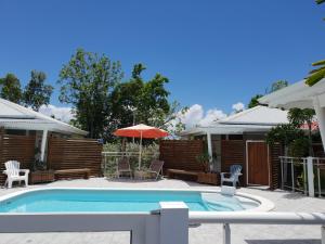 a pool with chairs and an umbrella next to a house at Les Jardins des Alizés in Saint-François