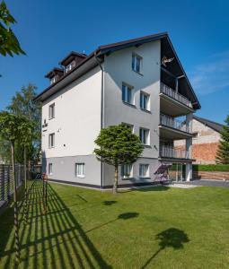 ein großes weißes Gebäude mit einem Baum im Hof in der Unterkunft Villa Milla in Łeba