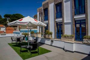 eine Terrasse mit Tischen, Stühlen und einem Sonnenschirm in der Unterkunft Hotel Varandazul in Palmela