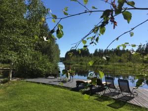a picnic table and chairs on a boardwalk next to a lake at Rantakatti Apartments in Punkaharju
