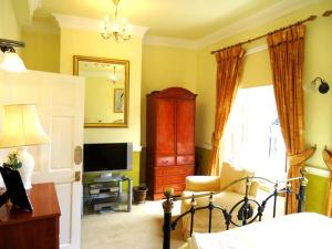 a bedroom with a bed and a dresser and a television at The Georgian House in Watchet