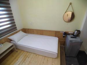 a white bed sitting next to a wall next to a lamp at 玖拾捌民宿-98bnb in Hualien City