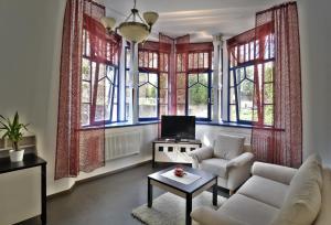 a living room with a couch and a tv and windows at Luxury Spa & Wellness Vila Valaška in Luhačovice