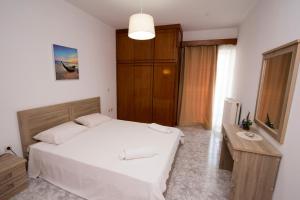 a bedroom with a white bed and a wooden cabinet at KOS Family House in Psalidi