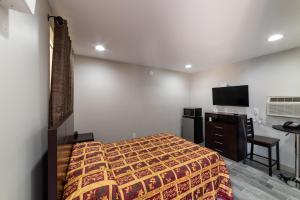 a bedroom with a bed and a desk and a television at Budget Inn & Suites Baton Rouge in Baton Rouge