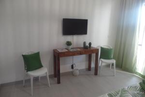 カバナス・デ・タビラにあるCabanas de Tavira apartmentのデスク、椅子2脚、テレビが備わる客室です。