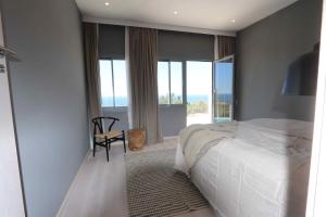 a bedroom with a bed and a chair and windows at Finca Vista in Marbella +41 photos