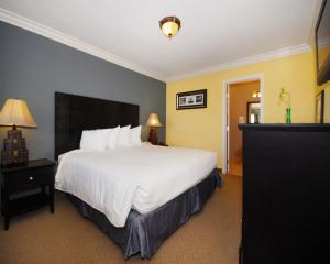 Una habitación de hotel con una gran cama blanca y paredes amarillas. en Solaire Inn & Suites, en Santa Maria