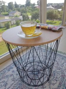 una tazza di tè seduta su un tavolo di fronte a una finestra di Aukštaičių apartamentai a Rokiškis