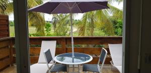 a table and chairs with an umbrella on a balcony at Jardin D'eden in Le Moule
