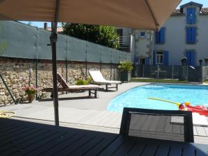a swimming pool with an umbrella and some chairs at Chambres d'Hôtes L'Albinque in Castres