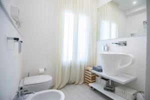 La salle de bains blanche est pourvue de toilettes et d'un lavabo. dans l'établissement White Apartment, à Forte dei Marmi
