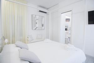 a white bedroom with a white bed and a mirror at White Apartment in Forte dei Marmi