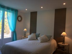 una camera da letto con un letto con tende blu e una finestra di Le Mapillon a Dieulefit